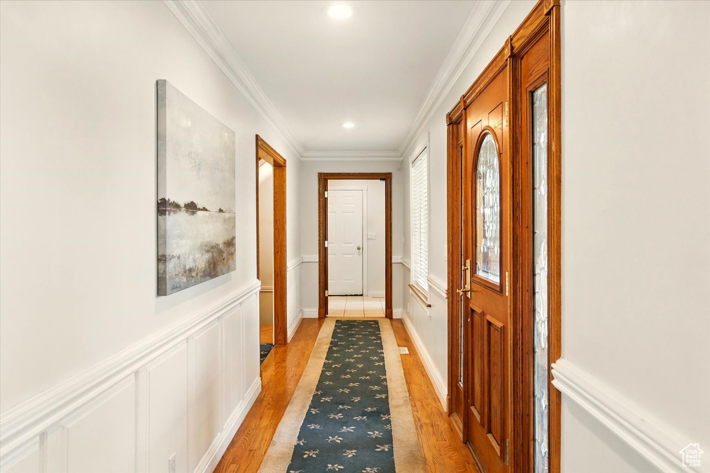 Doorway to outside with light wood-style floors, ornamental molding, recessed lighting, and wainscoting