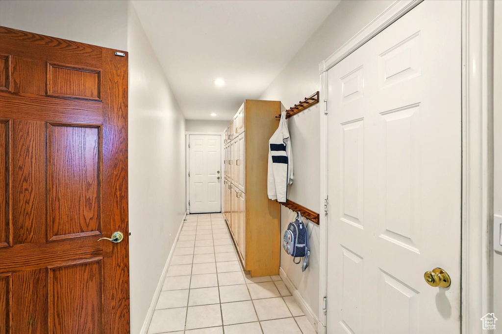 Hallway featuring light tile patterned floors, baseboards, and recessed lighting