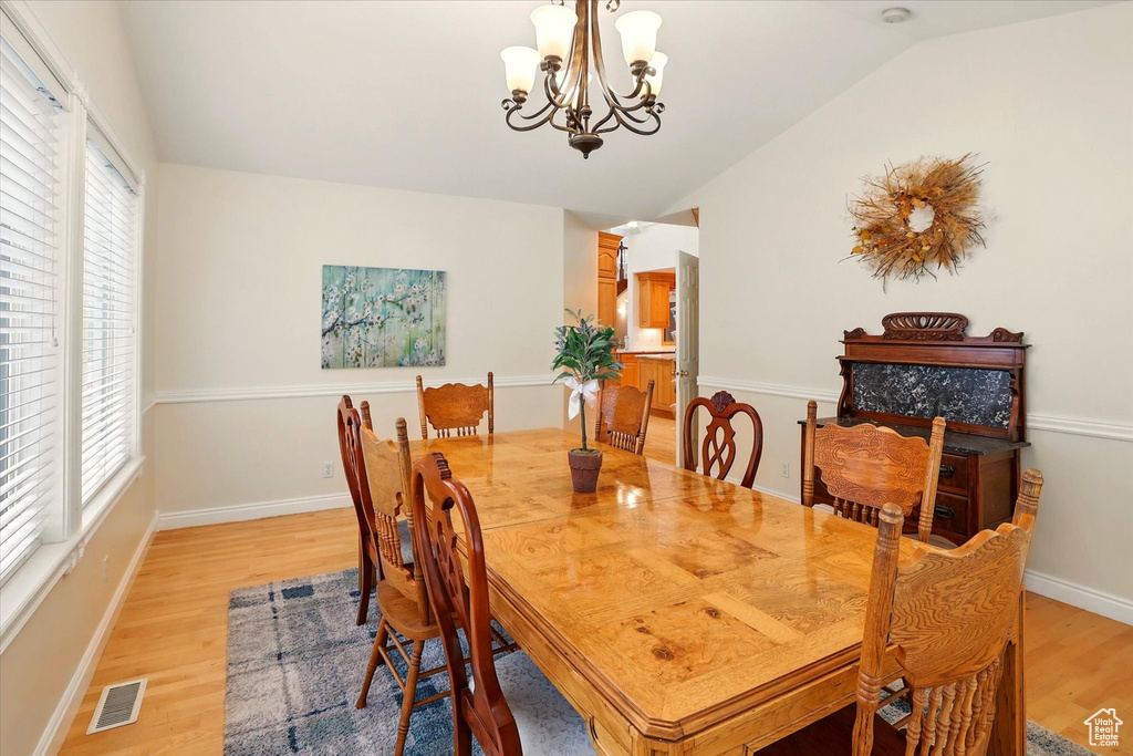 Dining space featuring lofted ceiling, light wood-style floors, a chandelier, and baseboards