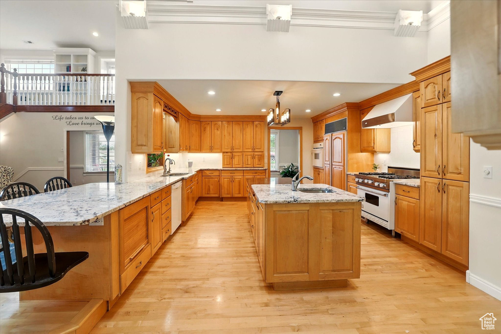 Kitchen featuring range with gas stovetop, wall chimney range hood, dishwasher, a sink, and a chandelier