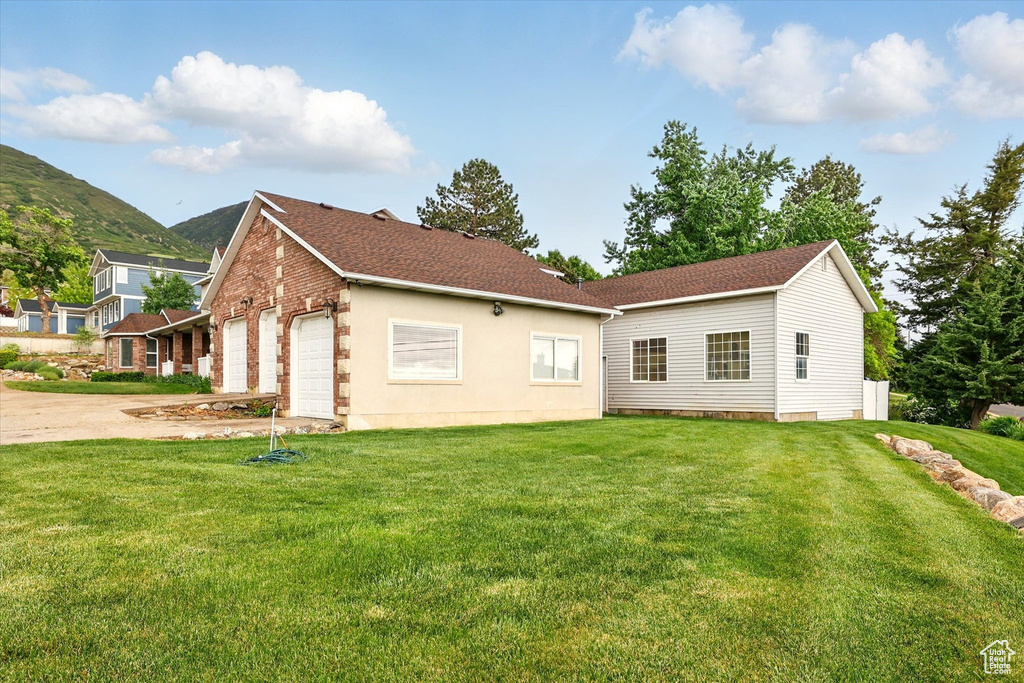 Rear view of house with a yard, a garage, driveway, and a mountain view