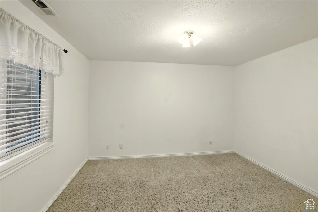 Carpeted spare room featuring baseboards