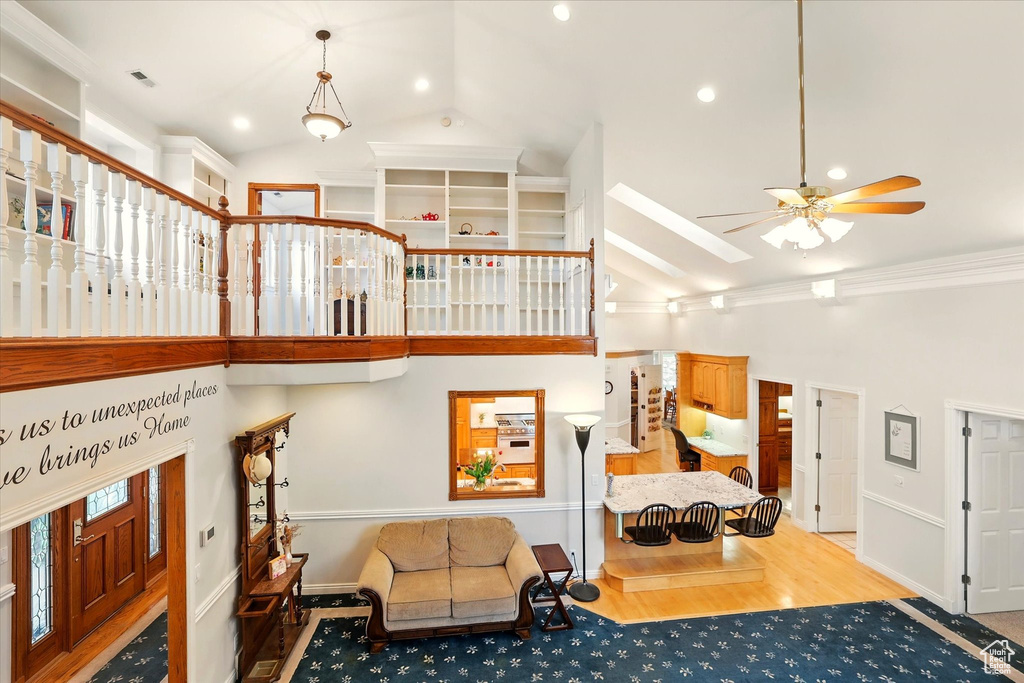 Living area with high vaulted ceiling, a ceiling fan, wood finished floors, recessed lighting, and baseboards
