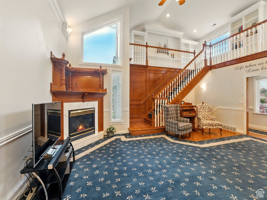 Living room featuring high vaulted ceiling, a ceiling fan, healthy amount of natural light, stairs, and a premium fireplace