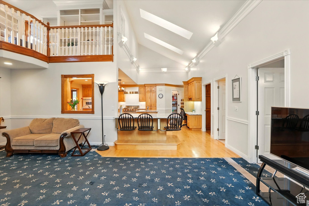 Living area with a skylight, light wood-style floors, and high vaulted ceiling