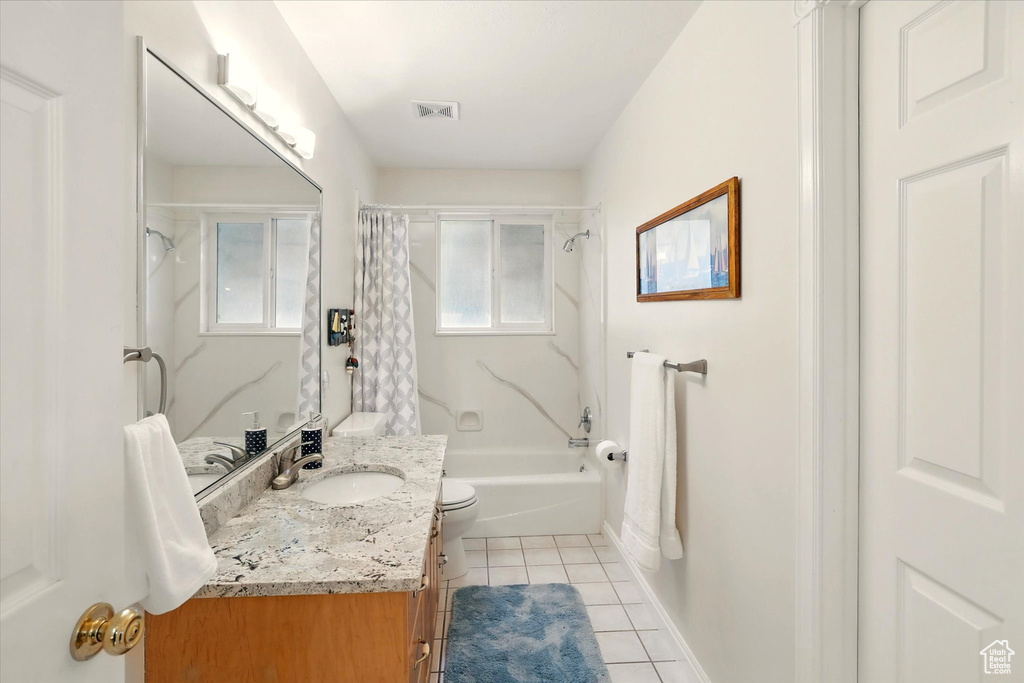 Bathroom featuring tile patterned floors, vanity, shower / bath combo with shower curtain, toilet, and baseboards