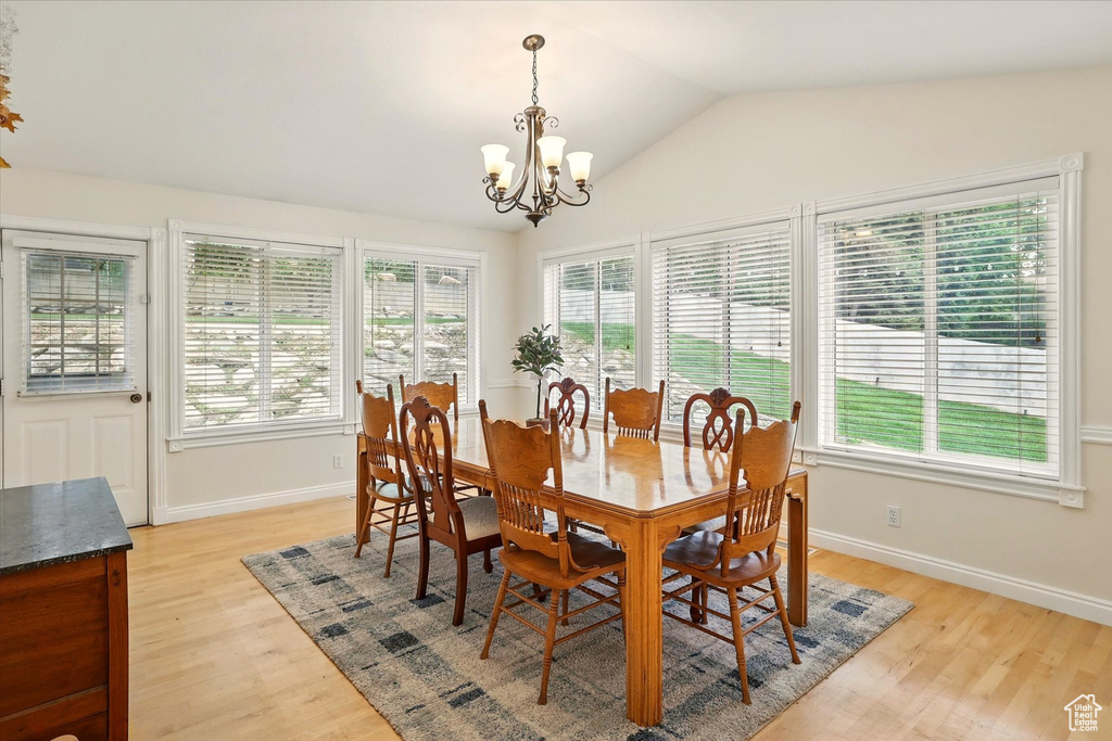 Dining room with plenty of natural light, a chandelier, light wood-style floors, and lofted ceiling