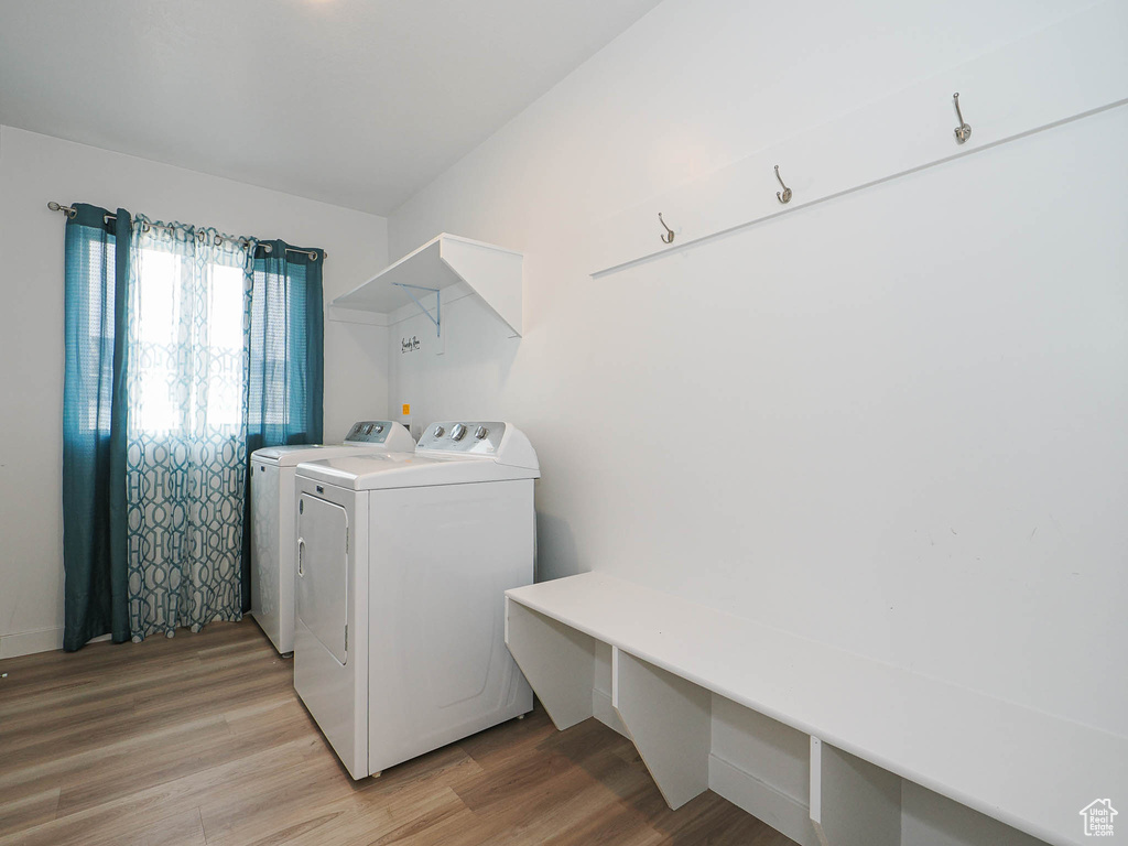 Clothes washing area with separate washer and dryer and light wood-style floors