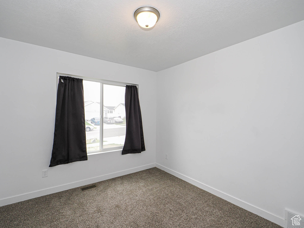 Spare room with baseboards, carpet flooring, and a textured ceiling