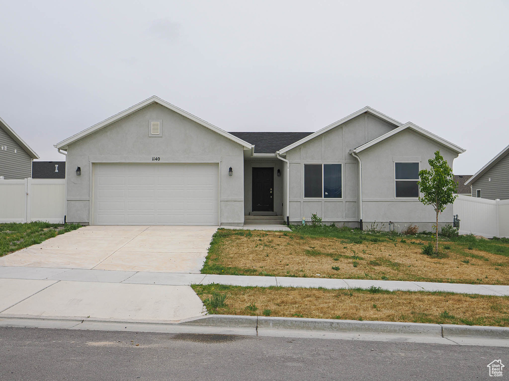 Single story home with a garage, fence, stucco siding, and driveway