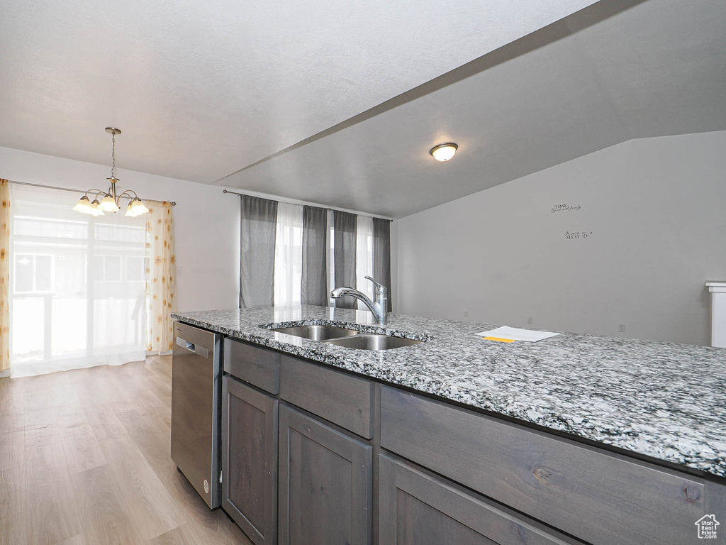 Kitchen with stainless steel dishwasher, a chandelier, a sink, light wood-style flooring, and healthy amount of natural light