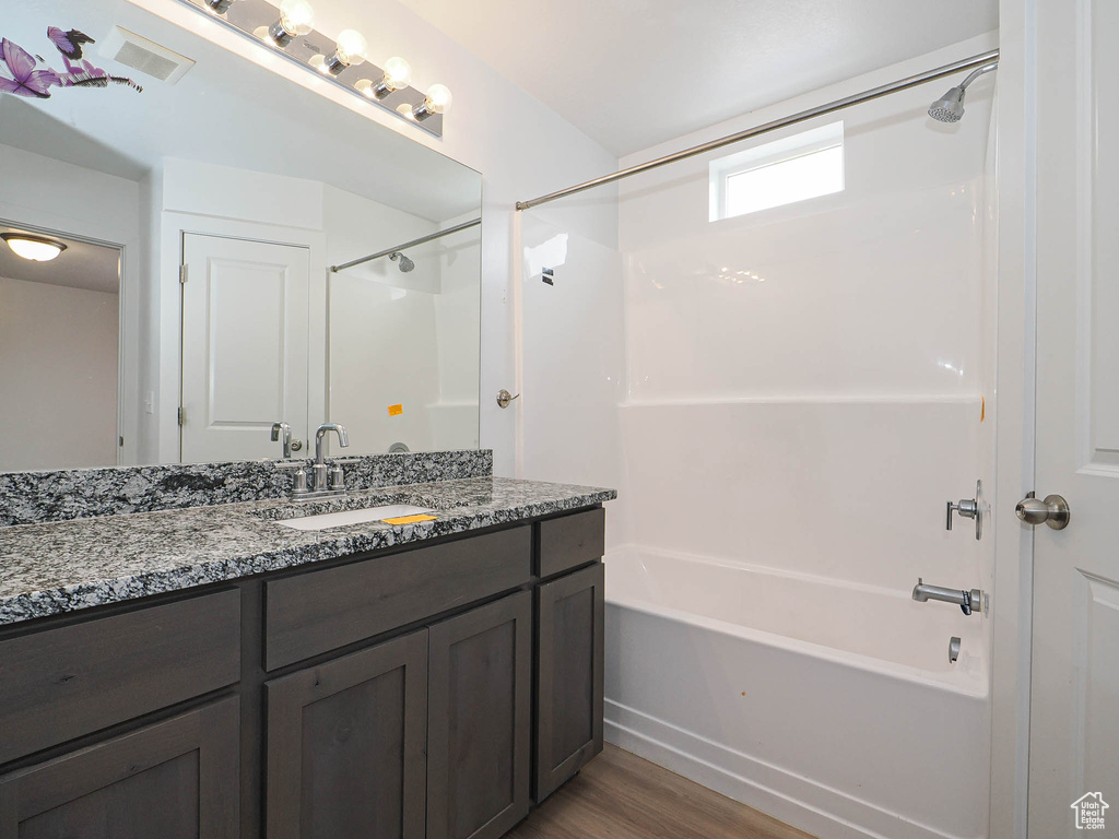 Full bath with wood finished floors, washtub / shower combination, and vanity