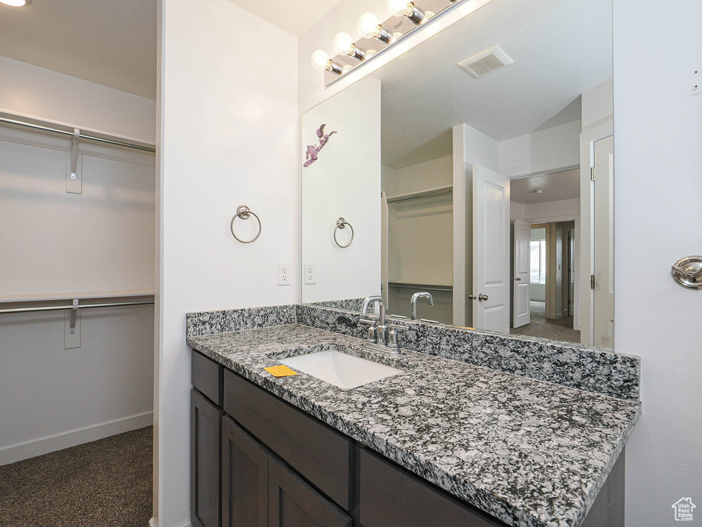 Bathroom with vanity, a walk in closet, and baseboards
