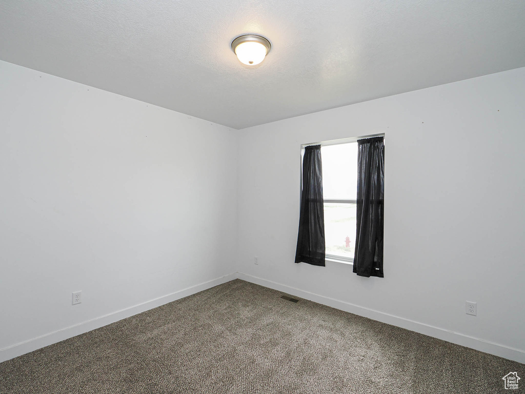 Spare room featuring baseboards and carpet flooring