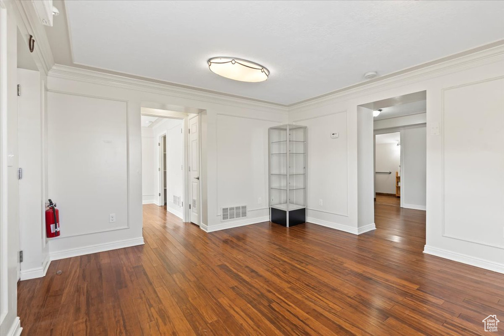 Unfurnished room featuring ornamental molding, wood finished floors, baseboards, and a smoke detector