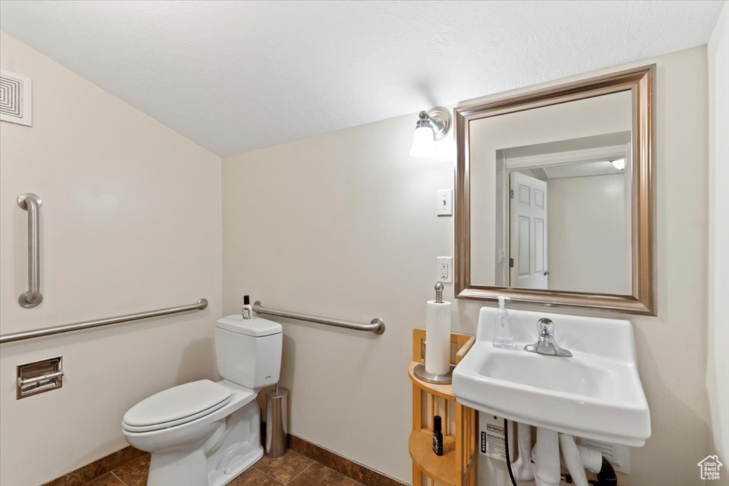 Half bath with toilet, baseboards, and a sink