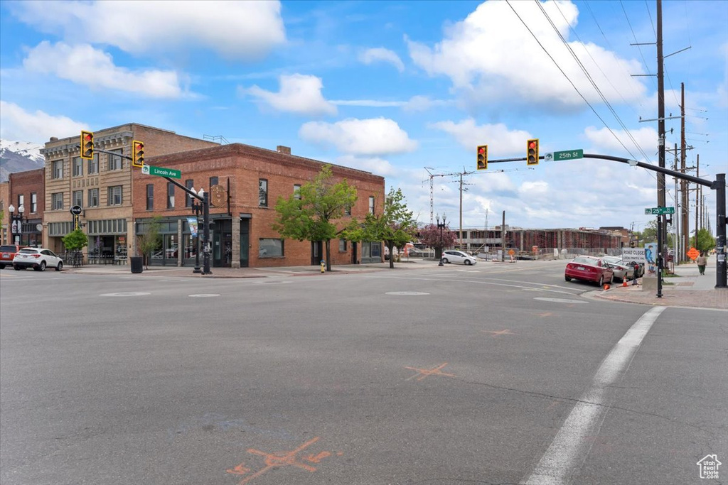 View of asphalt road featuring traffic lights, street lights, sidewalks, and curbs