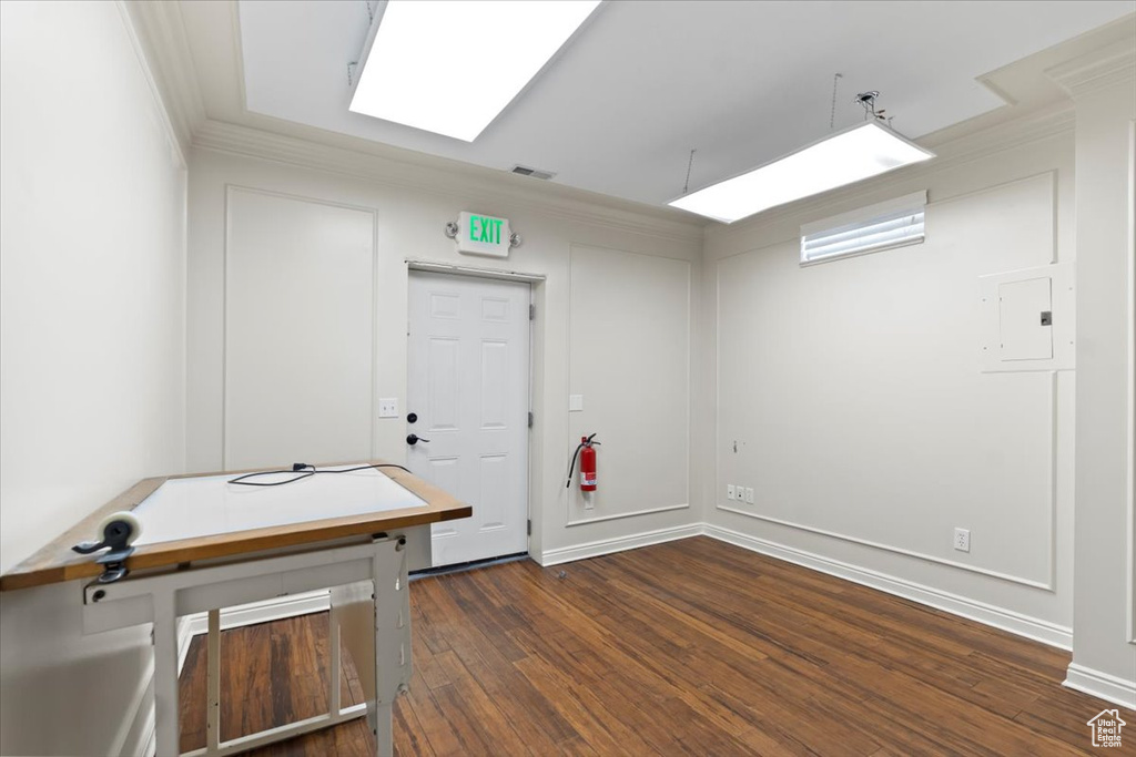 Interior space with a skylight, ornamental molding, and dark wood finished floors