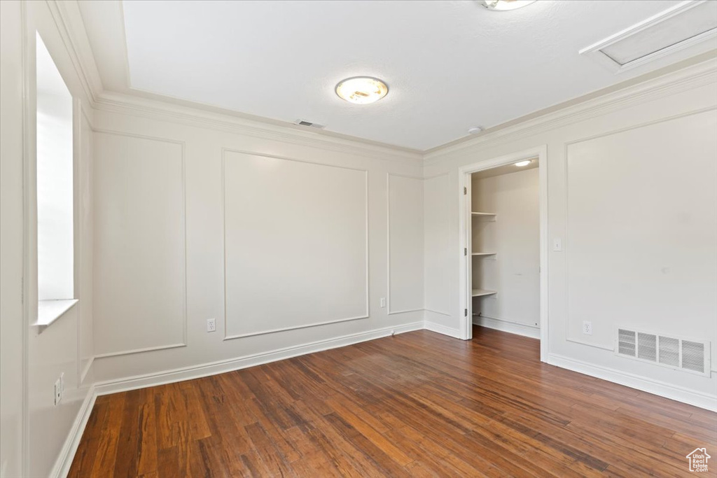 Spare room with ornamental molding, a decorative wall, dark wood-type flooring, and attic access