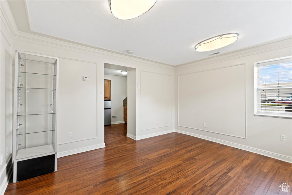 Unfurnished bedroom with wood finished floors, ornamental molding, and baseboards