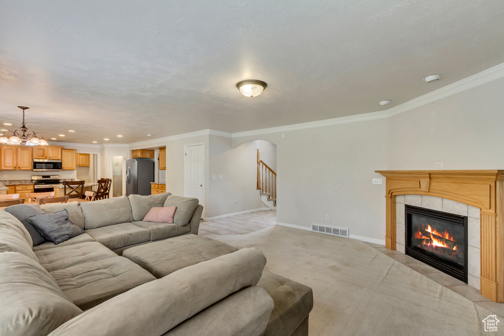 Living area featuring stairs, a fireplace, baseboards, a chandelier, and crown molding