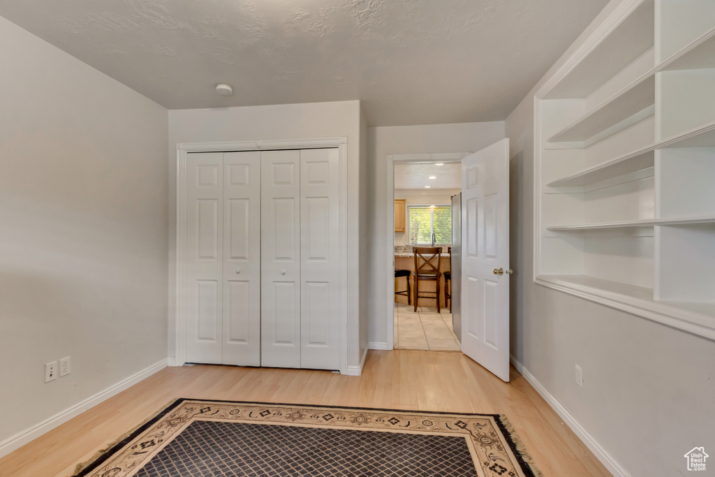 Unfurnished bedroom featuring light wood-type flooring, a closet, and baseboards