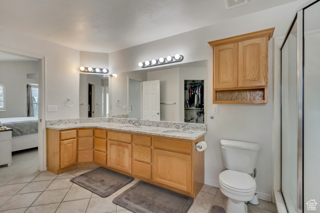 Bathroom featuring tile patterned floors, connected bathroom, double vanity, toilet, and a closet