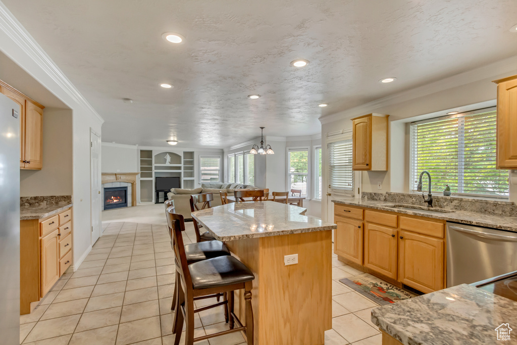 Kitchen featuring a sink, crown molding, a kitchen island, open floor plan, and a lit fireplace