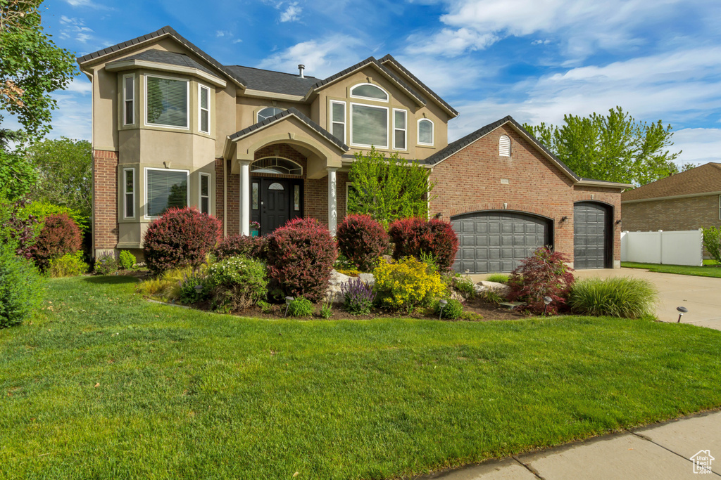 Traditional-style house with concrete driveway, brick siding, an attached garage, and stucco siding