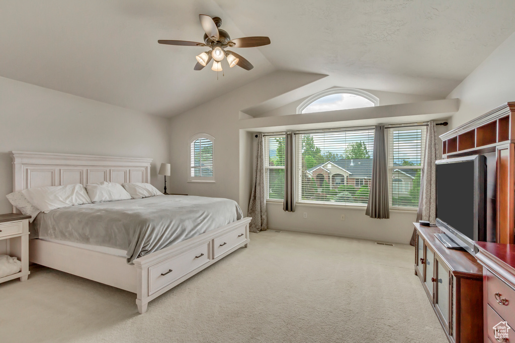 Bedroom featuring vaulted ceiling, light colored carpet, and ceiling fan