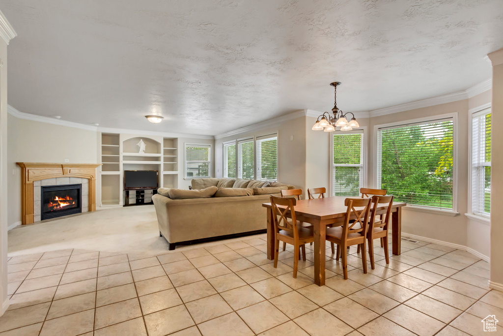 Dining area with built in shelves, a chandelier, baseboards, a fireplace, and ornamental molding