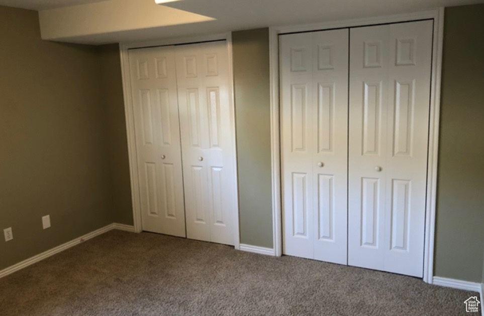 Unfurnished bedroom featuring carpet flooring, multiple closets, and baseboards
