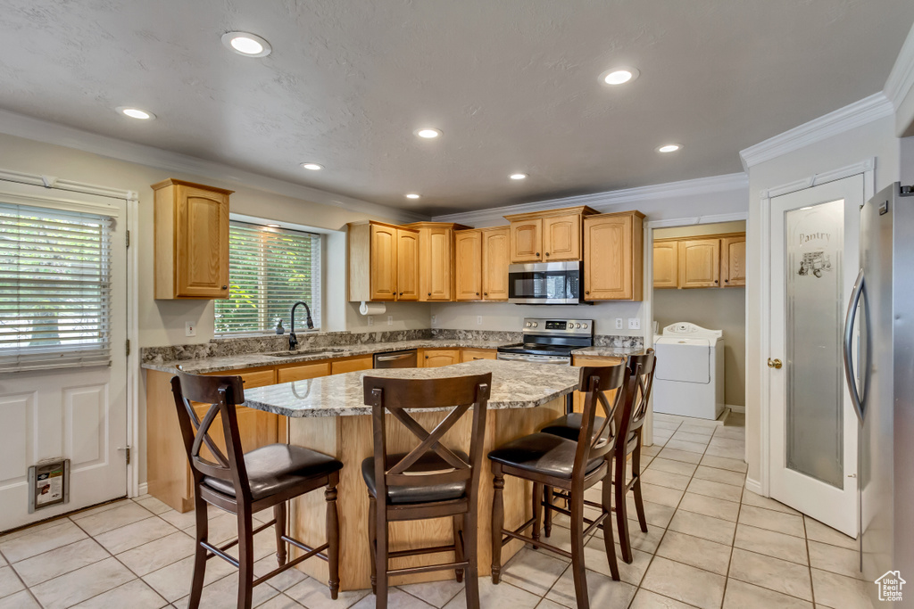 Kitchen featuring appliances with stainless steel finishes, washer / clothes dryer, a sink, ornamental molding, and recessed lighting