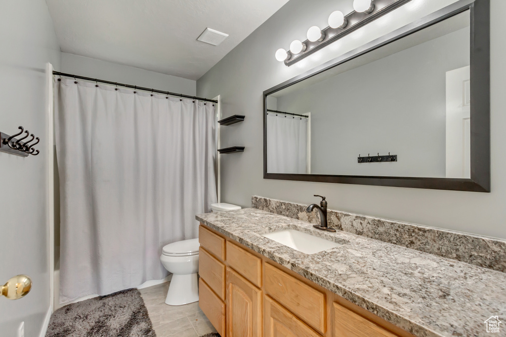 Full bath featuring toilet, vanity, and curtained shower