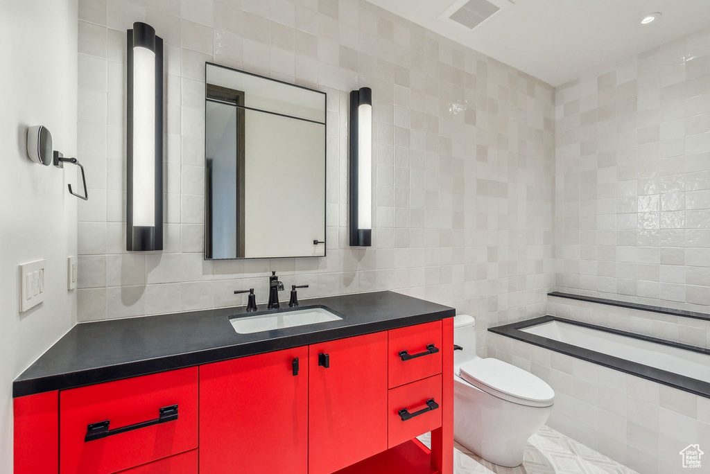 Full bath with tile walls, vanity, toilet, tiled bath, and decorative backsplash