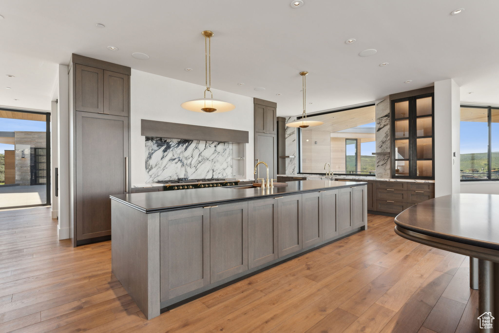 Kitchen with backsplash, plenty of natural light, a center island with sink, recessed lighting, and expansive windows