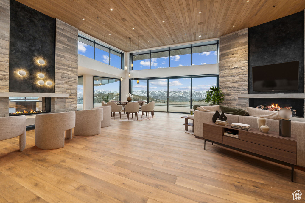Living area featuring a fireplace, a high ceiling, wooden ceiling, wood-type flooring, and recessed lighting