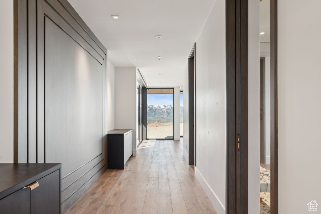 Hallway with light wood finished floors, expansive windows, and baseboards