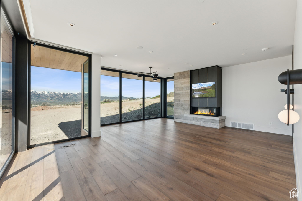 Unfurnished living room featuring expansive windows, wood finished floors, a fireplace, and a mountain view