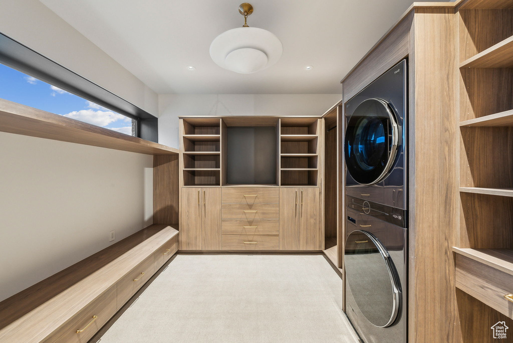Washroom with estacked washer and dryer and light colored carpet