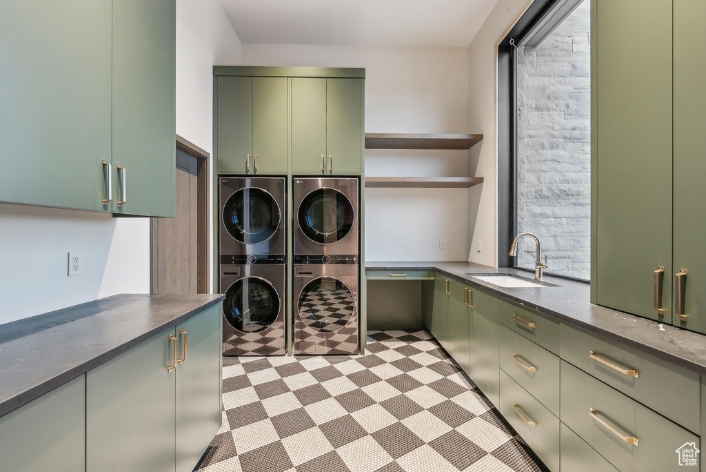 Laundry area featuring cabinet space, stacked washer / drying machine, and light floors