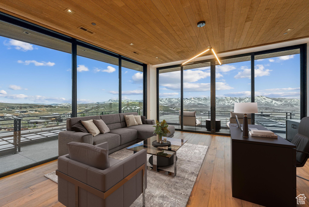 Living area with floor to ceiling windows, wood ceiling, light wood-style flooring, and a mountain view