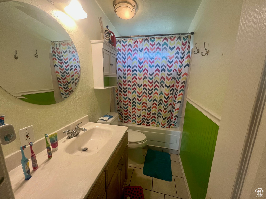 Bathroom with toilet, tile patterned floors, vanity, and shower / bath combo with shower curtain