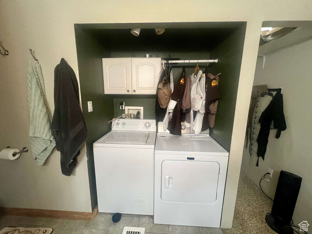 Laundry room featuring washing machine and clothes dryer, cabinet space, and baseboards