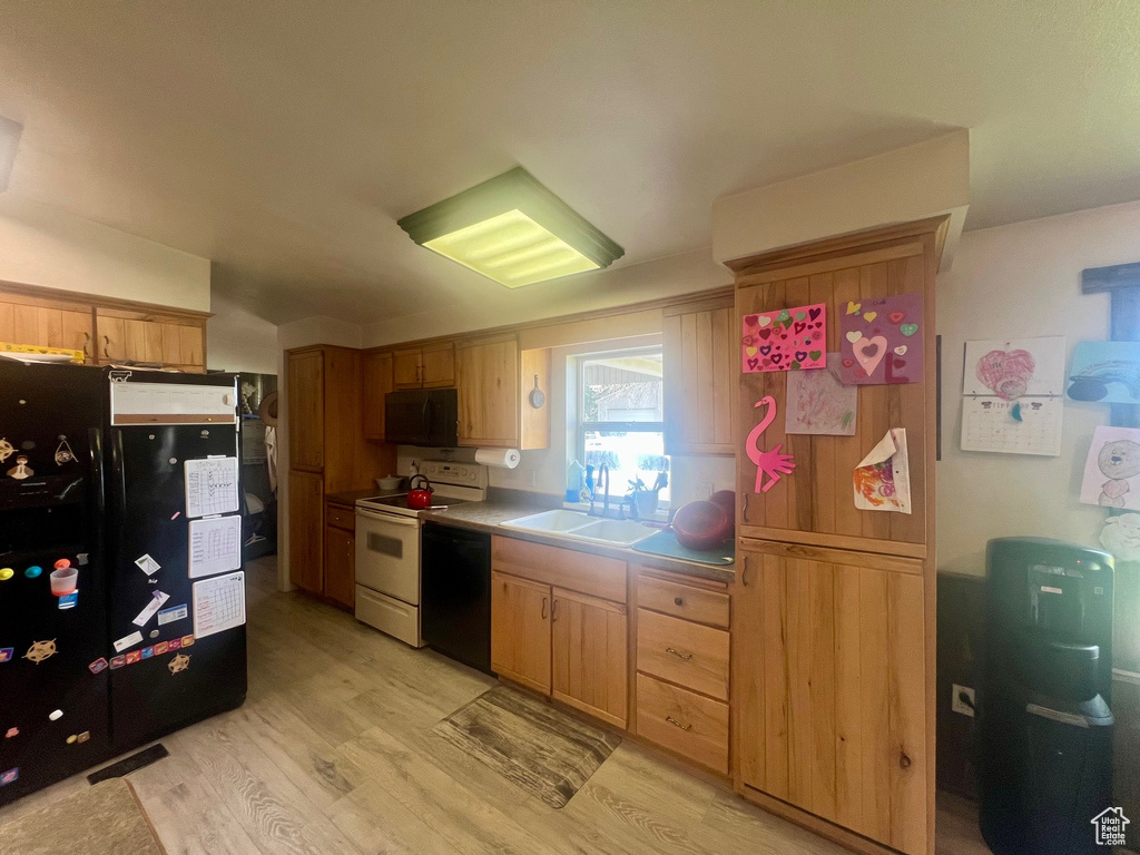 Kitchen featuring black appliances, a sink, light wood-style flooring, and light countertops