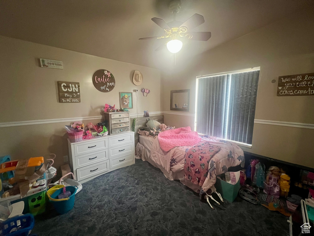 Bedroom with dark carpet, vaulted ceiling, and ceiling fan