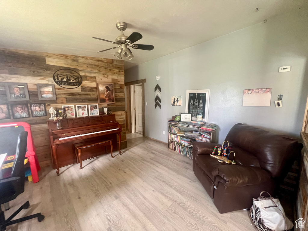 Living area featuring wooden walls, a ceiling fan, and wood finished floors