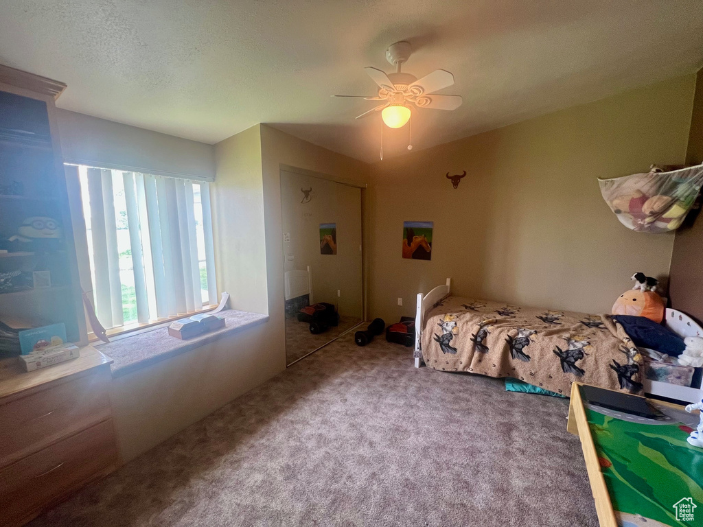 Carpeted bedroom featuring ceiling fan