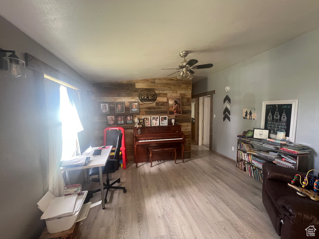 Office space featuring wooden walls, ceiling fan, and wood finished floors