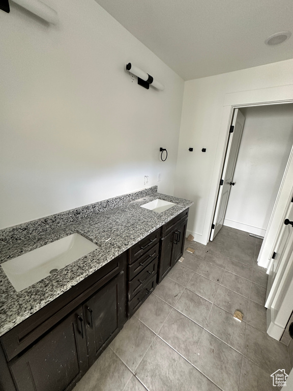 Bathroom featuring tile patterned flooring, double vanity, and baseboards